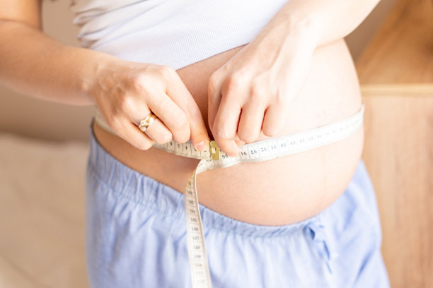孕妇测肚子。幸福美丽的孕妇用卷尺量肚子。孕、药保健理念。图片下载