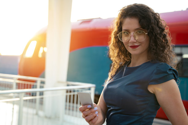 时髦的卷发女孩在火车站手持空卡图片下载