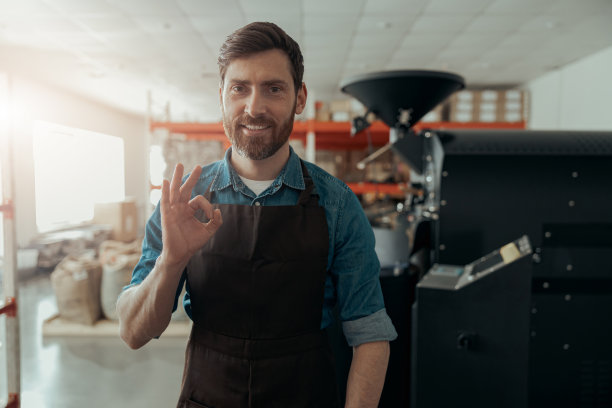 自己的小咖啡厂背景上微笑的企业主肖像展示ok标志图片下载