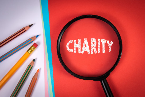慈善机构。放大镜，铅笔和彩色纸张图片下载