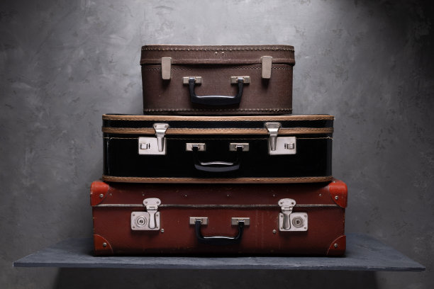 桌子上有一堆行李箱。靠近墙壁的旧手提箱作为旅行概念的想法图片下载