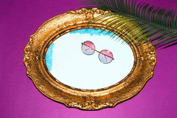 太阳镜在复古框架与蓝色背景，框架上的紫色背景与棕榈叶，创意夏季设计图片下载