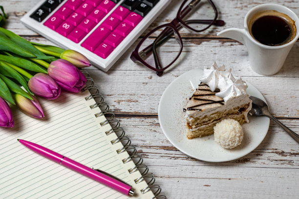 假日在金融领域，视图桌面郁金香咖啡与蛋糕和笔记本与计算器在木制光背景特写图片下载