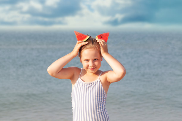 快乐可爱的小女孩与西瓜在夏天的海滩肖像。夏天的一天。海上度假概念图片下载