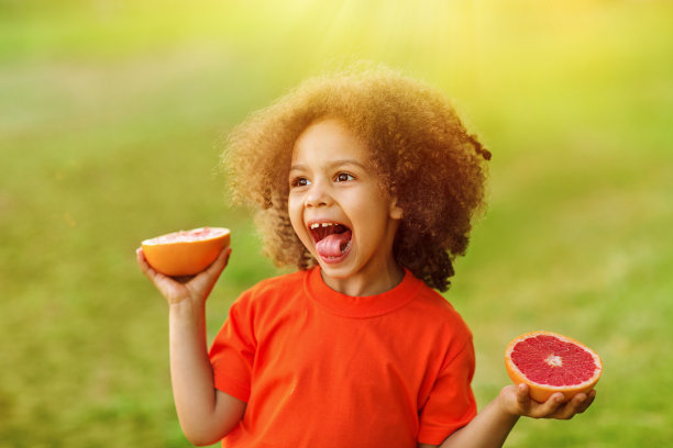 快乐的黑人女孩在户外玩她手里的橙子图片下载