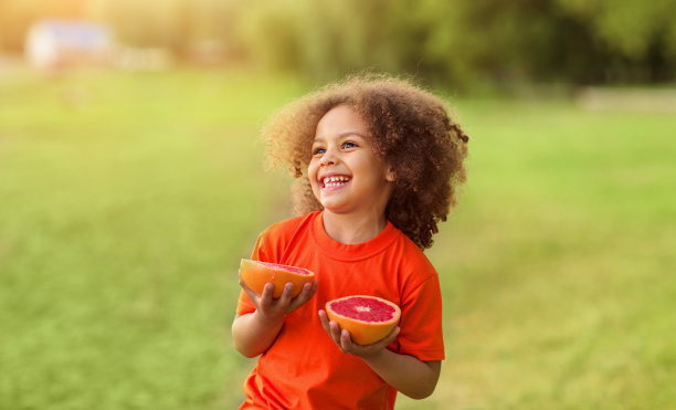 快乐的黑人女孩在户外玩她手里的橙子图片下载
