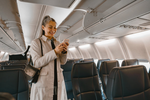 飞机在机场降落时，微笑的乘客在机舱内放置手机架图片下载