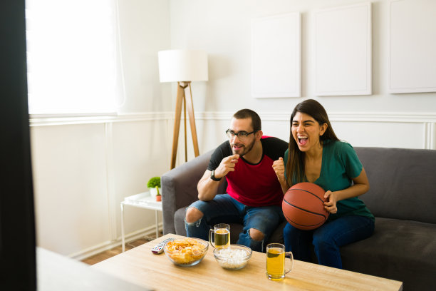 幸福的女人和男人享受着电视上的篮球比赛图片下载
