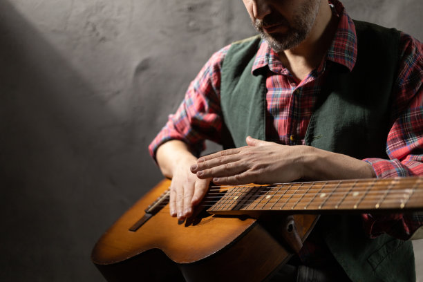 男人在弹原声吉他。音乐家和工作室持有经典原声吉他图片下载
