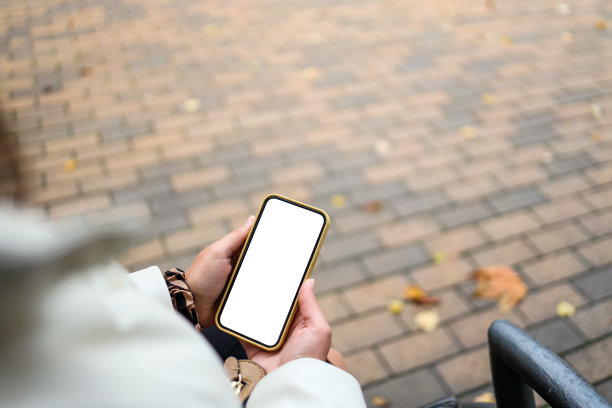俯视图的一个女人的手拿着智能手机与白色的空白屏幕。复制空间在秋天的花园。女性用手机看文字和视频图片下载
