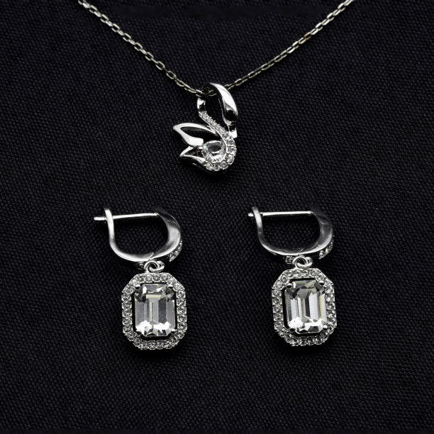 特写微距摄影，天鹅和八角形钻石耳环和项链珠宝套装布匹黑色背景。图片下载