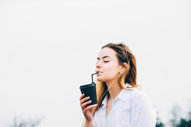一个漂亮的女性享受着一杯饮料，微笑着，闭着眼睛，拷贝空间图片下载