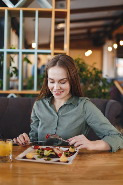 一个漂亮的女孩在餐厅里喝着白(红)酒吃饭。图片下载