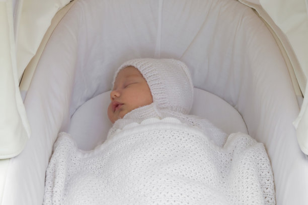 刚出生的男孩在户外散步时闭着眼睛睡在白色的婴儿车里。温暖的针织服装。特写镜头。一个月大的婴儿。图片下载