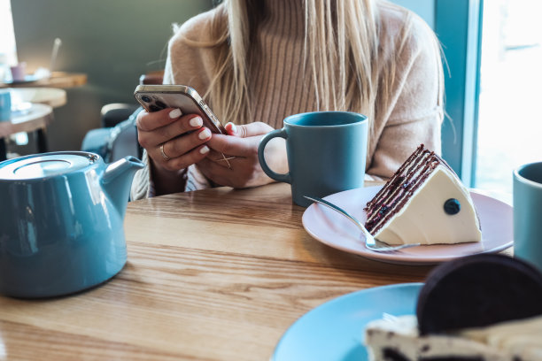 一个女人靠在吧台上，用手机发短信，手离得很近图片下载