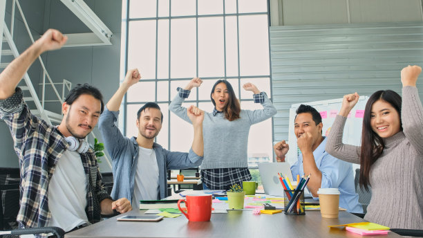 业务成功的公司，创意团队微笑着与合作伙伴在成功的工作后举起手，快乐的团队在会议室办公室一起为成就举手图片下载