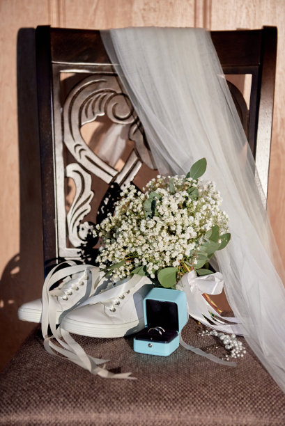 新娘花束与缎带，女人的鞋子，面纱和两个黄金结婚戒指在椅子上，复制空间。结婚的概念图片下载