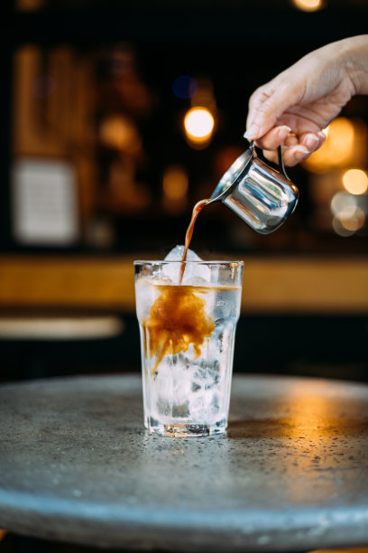 将浓缩咖啡倒入冰块中制作冰美式咖啡图片下载