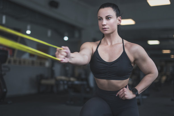 肌肉发达的女性在健身房用黄色橡皮筋热身图片下载
