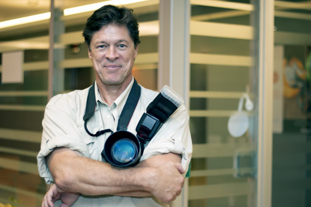 微笑的摄影师拿着他的相机。图片下载