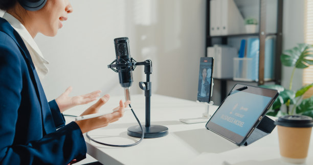 年轻的亚洲女商人用智能手机录制内容，在工作室办公室用平板电脑播放播客。图片下载