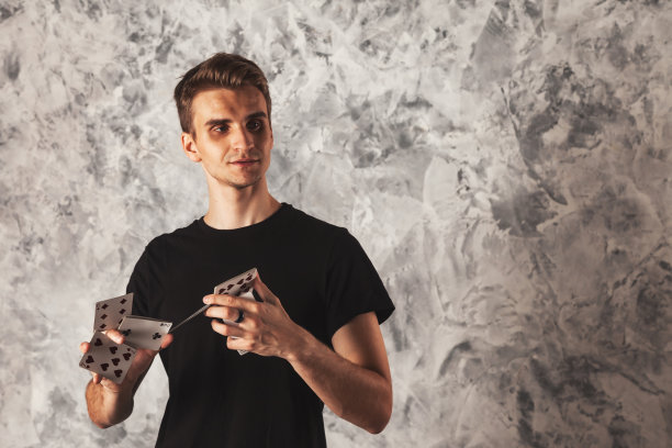 肖像魔术师与赌博卡在灰色的墙壁背景图片下载