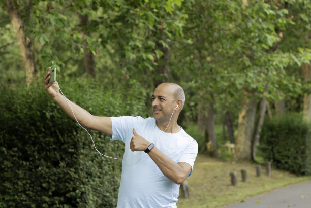 有趣的照片，一个无毛的白人男子在自然中进行视频通话，并对着相机微笑图片下载