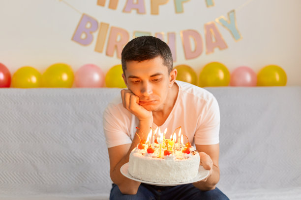 室内拍摄的年轻人无聊的感觉，有悲伤沮丧的表情，坐在沙发上，等待客人，独自在家庆祝生日，穿着白t恤。图片下载