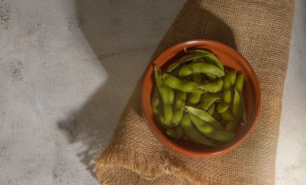 毛豆在碗里，在灰黑布和背景上，俯视，深色食物图片下载