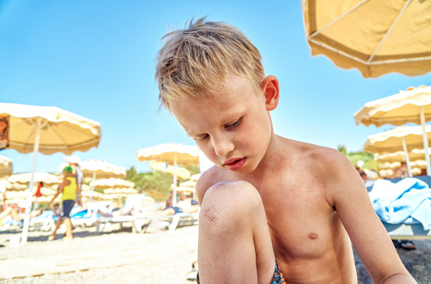 悲伤的学生膝盖脱皮坐在海边的海滩上图片下载