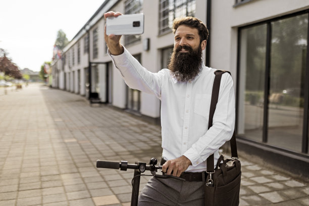 大胡子商人骑着电动摩托车自拍上班图片下载