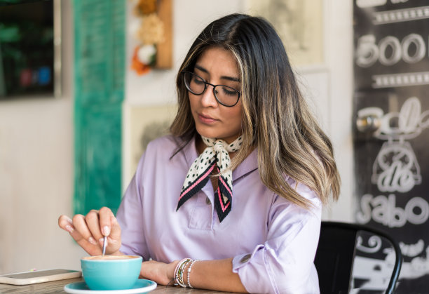 一个美丽的年轻女子与咖啡杯坐在咖啡店的肖像图片下载