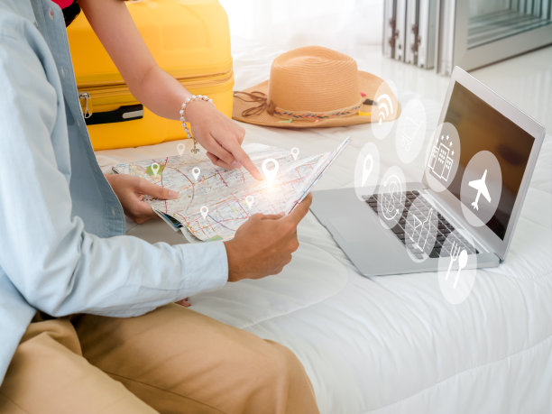 准备好旅行和度假的计划概念。靠近笔记本电脑的城市地图上虚拟的特写位置图标，由夫妇指点，在床上的旅行信息图标。暑假旅游计划。图片下载