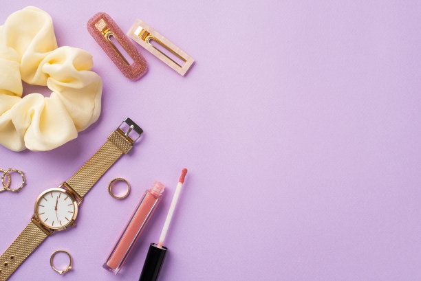 化妆美容的概念。顶视图照片发圈粉红色唇彩金腕表戒指和发夹在孤立的淡紫色背景与copyspace图片下载