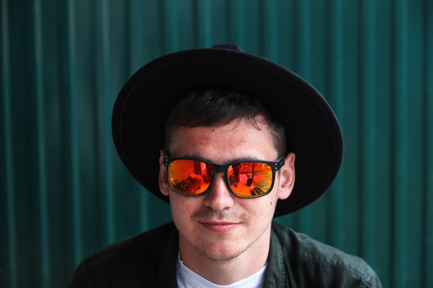 微笑着时尚的人。英俊微笑时尚潮人的肖像lambersexual模型。男人穿着红色偏振太阳镜。时尚男性在现代蓝色的背景。脸特写肖像图片下载