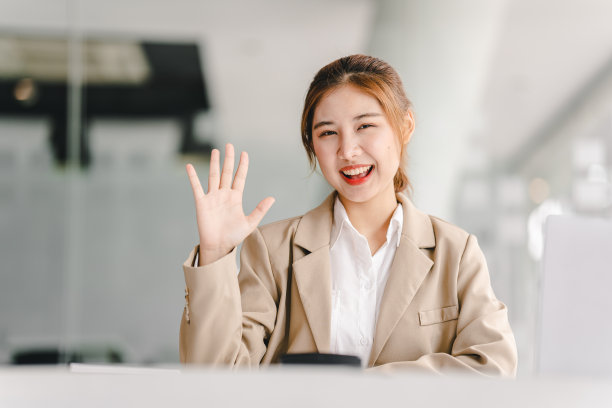 有魅力和快乐的年轻女学生在大学图书馆学习，坐在书桌前，使用笔记本电脑，有视频聊天，挥手，教育理念图片下载