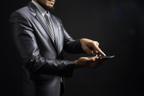 英俊自信的商人穿着西装，孤立地站在黑色背景上图片下载