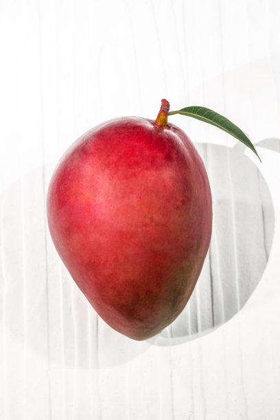 健康食品红色芒果水果有叶在白色的桌子背景。图片下载