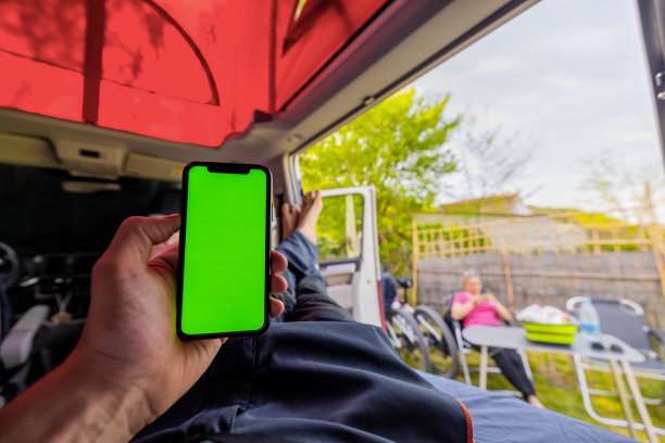 一名男子在露营车里放松地拿着绿色屏幕的手机图片下载