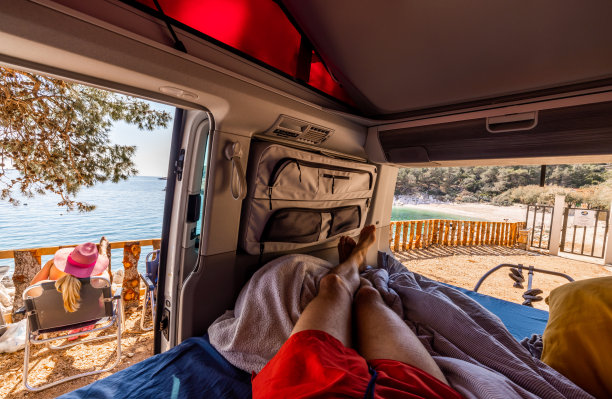 赤脚男人在露营车里放松，而女人坐在椅子上图片下载