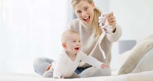 白人母亲和婴儿一起在明亮的白色卧室玩耍。快乐的年轻女性微笑着看着她可爱的男孩，而他正在看他的玩具。现代单亲家庭和儿童保育图片下载