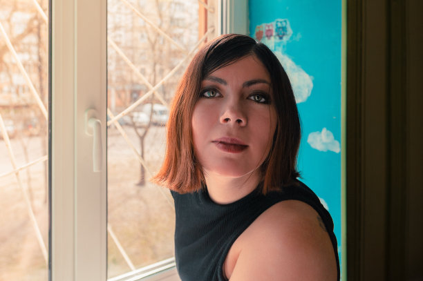 特写肖像，一个黑头发微笑的年轻女子在黑色的衣服靠近窗口图片下载