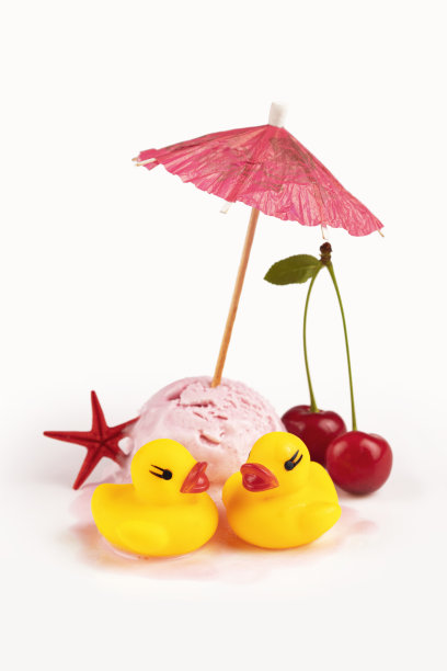 融化的樱桃冰淇淋配上纸伞和橡胶小鸭子图片下载