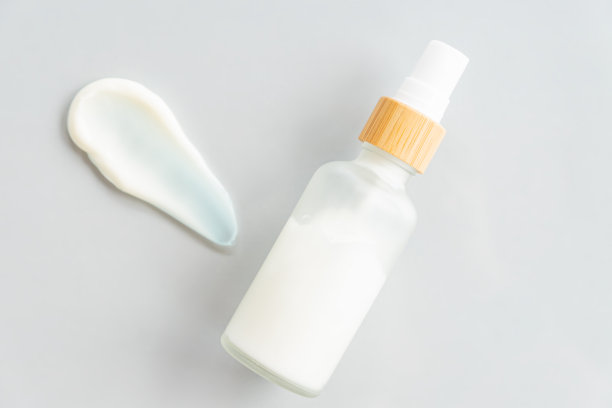 灰色背景的磨砂玻璃瓶保湿霜。天然环保美容产品品牌、包装设计。奶油涂片纹理图片下载