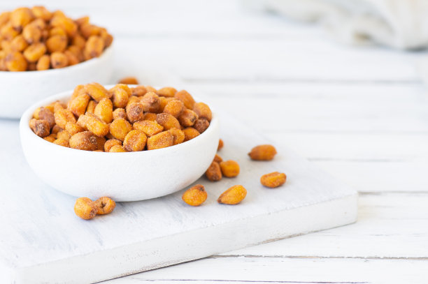 烤咸玉米坚果与香料和酱汁在碗在白色的桌子上，坚果的概念图片下载