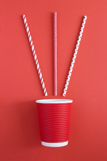 “零浪费”。红色背景的一次性红色纸杯和吸管。前视图。图片下载