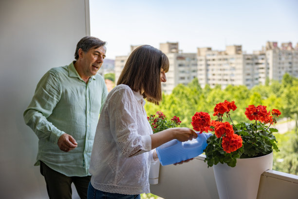十几岁的白人女儿和她的父亲在阳台上照顾室内植物图片下载