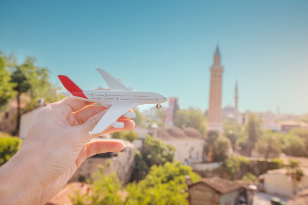 在安塔利亚老城著名的伊夫利尖塔的背景下，手握飞机。旅行和廉价航空的概念图片下载