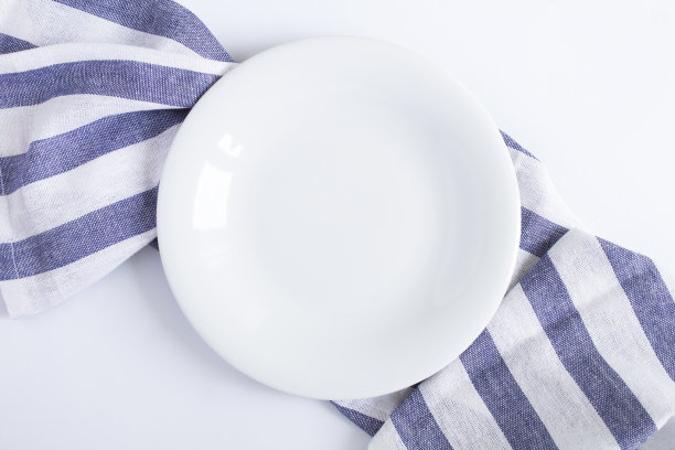 在白色背景上的条纹餐巾上的空白色盘子的俯视图。副本的空间。特写镜头。图片下载