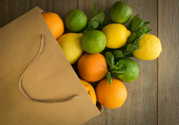 纸袋与新鲜柑橘水果在棕色的木制背景图片下载